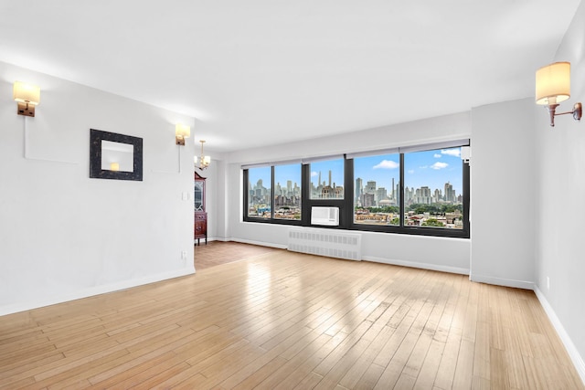 3343 14th St Unit 12B, Astoria, NY 11106 - spare room with radiator, a view of skyline, baseboards, and light wood finished floors