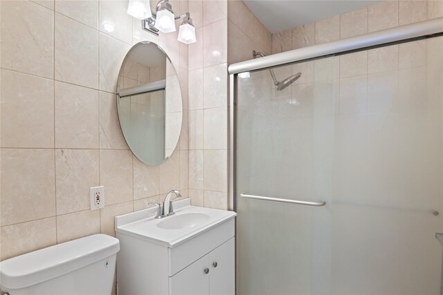 32 Pearsall Unit 3B, Glen Cove, NY 11542 - bathroom with tile walls, vanity, a stall shower, toilet, and backsplash