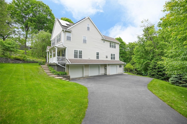 27 Millstream Ct, Pawling, NY 12564 - view of home's exterior with an attached garage, a lawn, roof mounted solar panels, stairs, and asphalt driveway