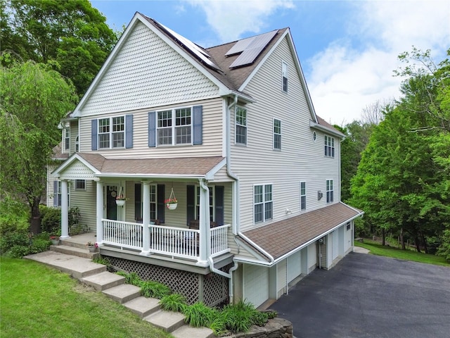 27 Millstream Ct, Pawling, NY 12564 - view of front of home with a porch, roof with shingles, roof mounted solar panels, asphalt driveway, and an attached garage