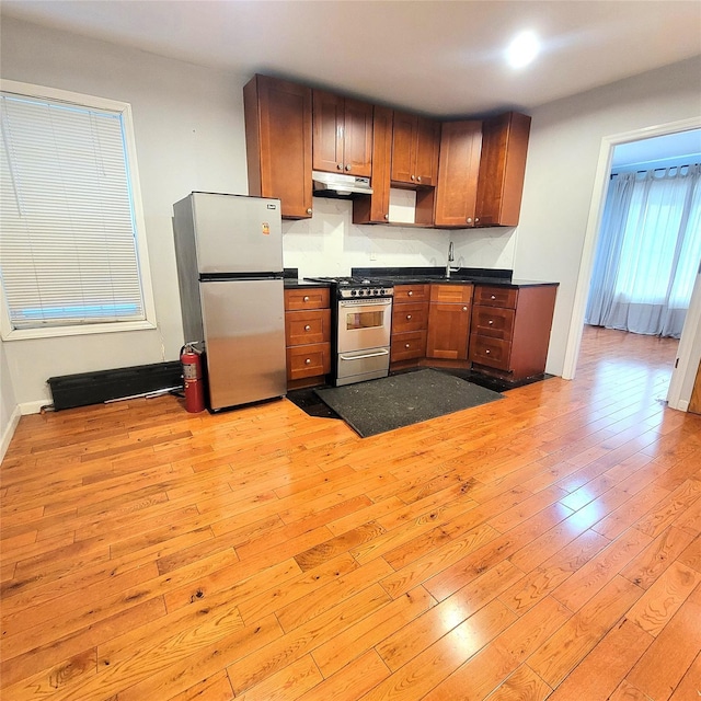 40-19 68th St, Woodside, NY 11377 - kitchen featuring appliances with stainless steel finishes, dark countertops, light wood-type flooring, under cabinet range hood, and a sink