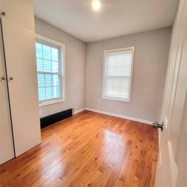 40-19 68th St, Woodside, NY 11377 - empty room featuring light wood-style flooring, baseboards, and a baseboard radiator