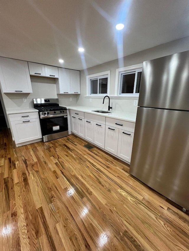 2411 Goshen Tpke, Middletown, NY 10941 - kitchen featuring appliances with stainless steel finishes, a sink, light countertops, light wood-style floors, and white cabinetry