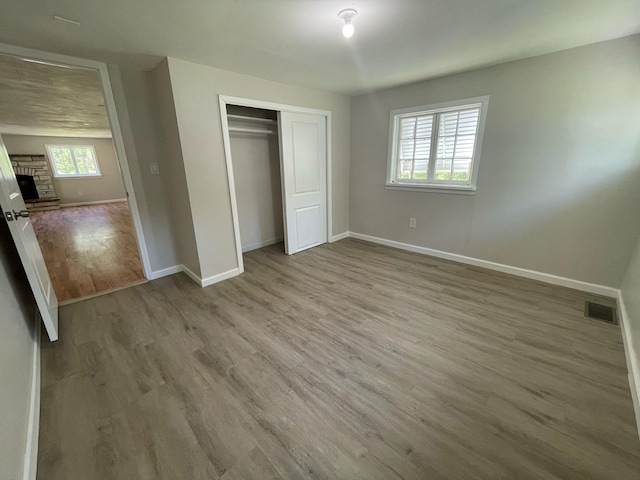 2411 Goshen Tpke, Middletown, NY 10941 - unfurnished bedroom featuring baseboards, wood finished floors, a fireplace with raised hearth, and a closet
