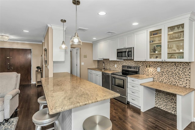 99 S Park # 308, Rockville Centre, NY 11570 - kitchen with appliances with stainless steel finishes, a kitchen bar, dark wood finished floors, a peninsula, and ornamental molding