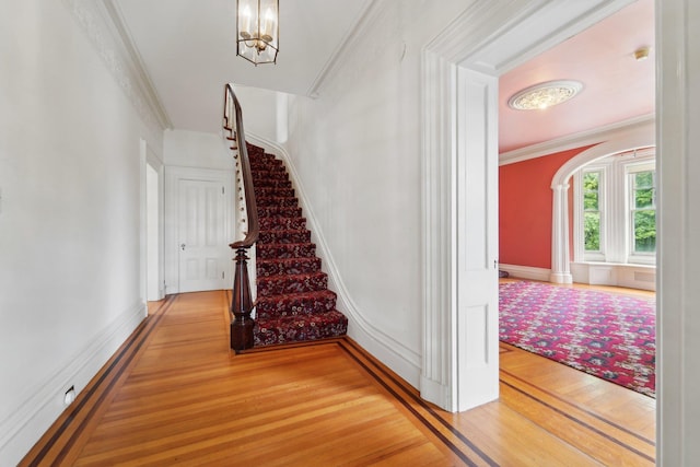 90 Main St, Chester, NY 10918 - stairs featuring wood finished floors, ornamental molding, a chandelier, and arched walkways