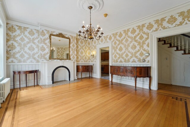90 Main St, Chester, NY 10918 - unfurnished living room with a chandelier, wainscoting, wallpapered walls, hardwood / wood-style flooring, and stairs