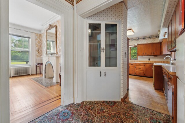 90 Main St, Chester, NY 10918 - kitchen featuring radiator, wallpapered walls, light wood-style flooring, a sink, and light countertops