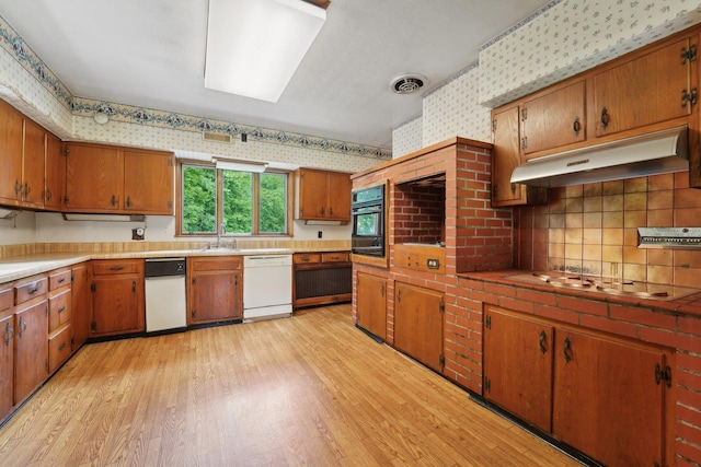 90 Main St, Chester, NY 10918 - kitchen with wallpapered walls, white dishwasher, under cabinet range hood, stovetop, and light wood finished floors