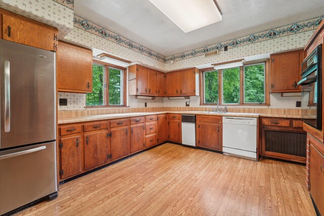 90 Main St, Chester, NY 10918 - kitchen with freestanding refrigerator, white dishwasher, light wood finished floors, light countertops, and brown cabinets