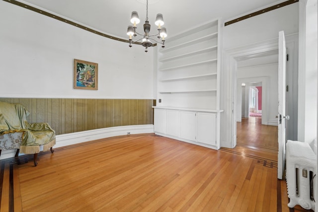 90 Main St, Chester, NY 10918 - unfurnished dining area featuring radiator heating unit, a chandelier, built in shelves, light wood-type flooring, and a wainscoted wall