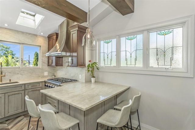 148-03 9th Ave, Whitestone, NY 11357 - kitchen featuring wall chimney exhaust hood, a breakfast bar, a skylight, tasteful backsplash, and plenty of natural light