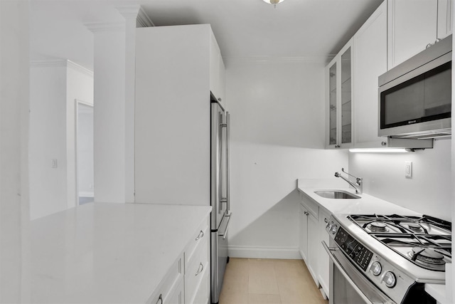 211 E 46th St Unit 14E, New York Manhattan, NY 10017 - kitchen featuring appliances with stainless steel finishes, a sink, white cabinetry, glass insert cabinets, and light countertops