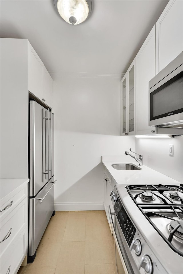 211 E 46th St Unit 14E, New York Manhattan, NY 10017 - kitchen with stainless steel appliances, a sink, white cabinets, and glass insert cabinets