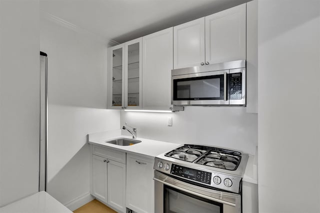 211 E 46th St Unit 14E, New York Manhattan, NY 10017 - kitchen featuring stainless steel appliances, a sink, light countertops, glass insert cabinets, and white cabinetry