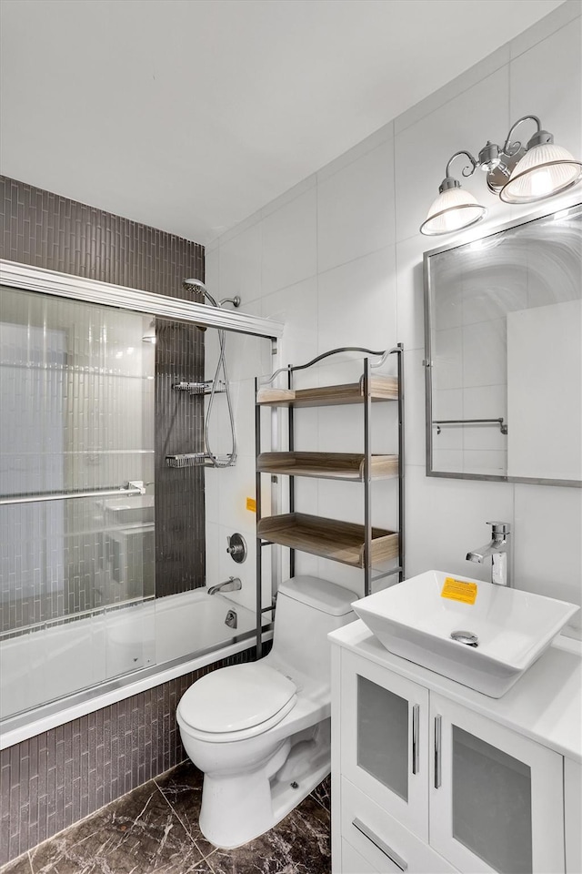 211 E 46th St Unit 14E, New York Manhattan, NY 10017 - bathroom with marble look tiles, bath / shower combo with glass door, vanity, and toilet