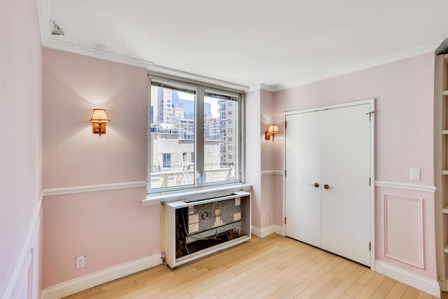 211 E 46th St Unit 14E, New York Manhattan, NY 10017 - bedroom featuring wood finished floors, crown molding, a closet, and baseboards