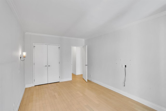 211 E 46th St Unit 14E, New York Manhattan, NY 10017 - unfurnished bedroom featuring ornamental molding, baseboards, light wood-style floors, and a closet