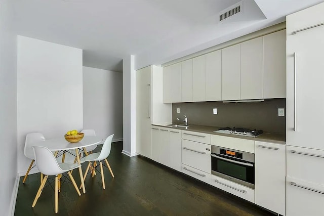 340 E 23rd St Unit 4L, New York Manhattan, NY 10010 - kitchen featuring stainless steel oven, modern cabinets, gas stovetop, baseboards, and dark wood finished floors