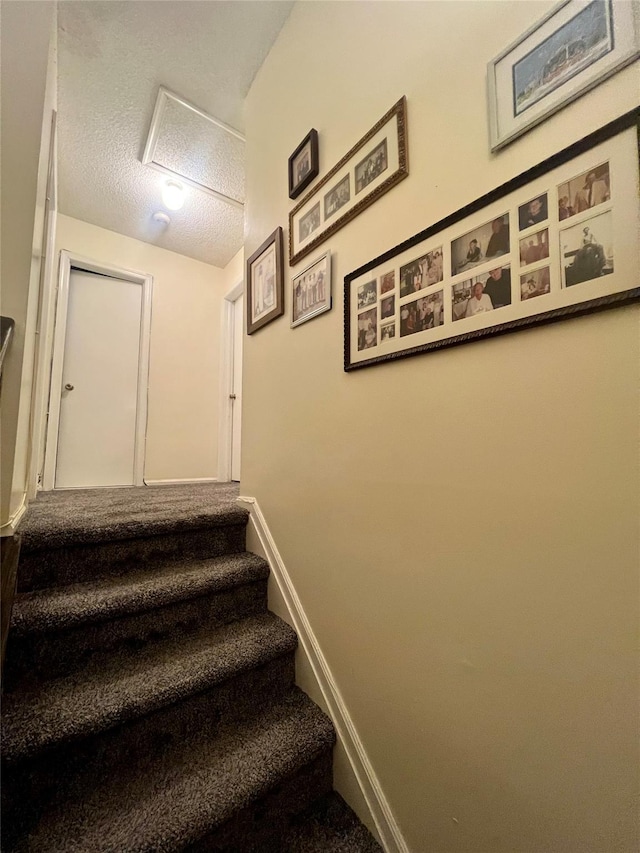 55 Winchester Ave, Peekskill, NY 10566 - staircase featuring baseboards, a textured ceiling, attic access, and carpet