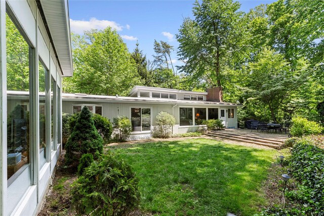 6 Harbor Hill Dr, Lloyd Harbor, NY 11743 - rear view of house featuring a lawn, a patio area, and a chimney