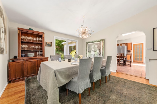 6 Harbor Hill Dr, Lloyd Harbor, NY 11743 - dining space featuring arched walkways, light wood-type flooring, a chandelier, baseboards, and lofted ceiling