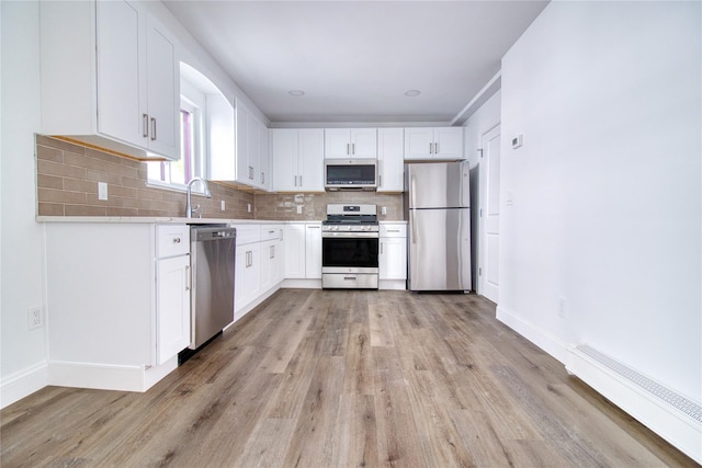 22 May Pl, Staten Island, NY 10312 - kitchen with stainless steel appliances, a baseboard heating unit, light wood-type flooring, backsplash, and light countertops