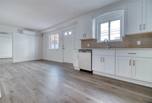22 May Pl, Staten Island, NY 10312 - kitchen featuring dishwasher, decorative backsplash, an AC wall unit, white cabinets, and light wood-style flooring