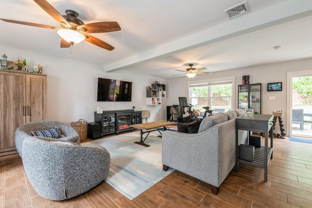 130 Shenandoah Blvd N, Nesconset, NY 11767 - living room featuring ceiling fan, beamed ceiling, healthy amount of natural light, wood finished floors, and a glass covered fireplace
