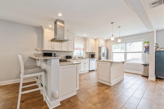130 Shenandoah Blvd N, Nesconset, NY 11767 - kitchen featuring island exhaust hood, white dishwasher, stainless steel fridge with ice dispenser, a kitchen breakfast bar, and tasteful backsplash