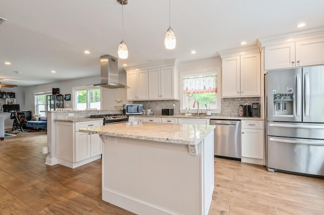 130 Shenandoah Blvd N, Nesconset, NY 11767 - kitchen featuring appliances with stainless steel finishes, island exhaust hood, backsplash, a kitchen island, and light wood-style floors
