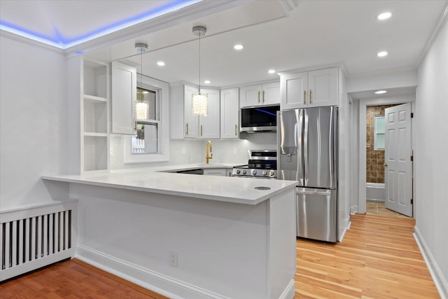 8 Lafayette Ave, Lake Grove, NY 11755 - kitchen featuring stainless steel appliances, radiator heating unit, a peninsula, white cabinets, and light wood-style flooring