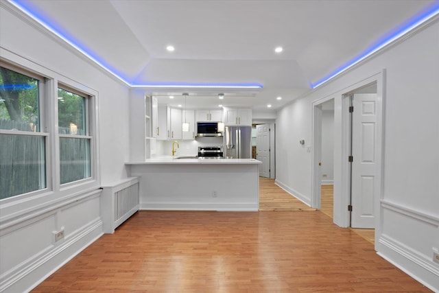 8 Lafayette Ave, Lake Grove, NY 11755 - kitchen featuring appliances with stainless steel finishes, white cabinets, a peninsula, light countertops, and a sink