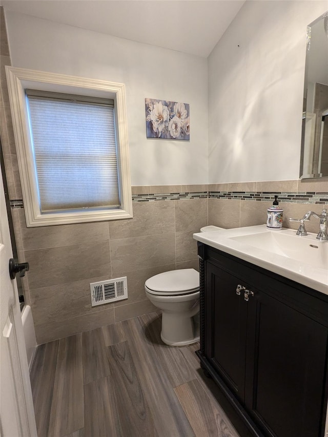 1114 Arden Ave, Staten Island, NY 10312 - bathroom featuring vanity, toilet, tile walls, wood finished floors, and a wainscoted wall