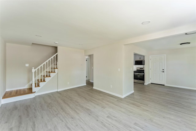 183-19 145th Ave, Springfield Gardens, NY 11413 - unfurnished living room with light wood finished floors, stairs, and baseboards