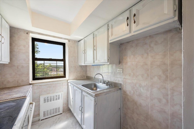 2545 Sedgwick Ave Unit 3B, Bronx, NY 10463 - kitchen with radiator heating unit, a sink, tile walls, white cabinetry, and light countertops