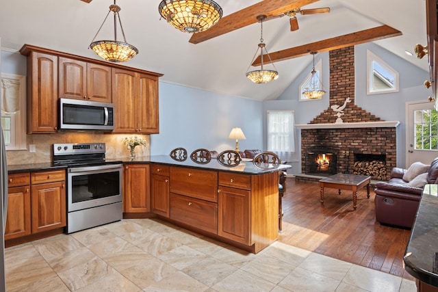 18 Chivalry Ln, Nesconset, NY 11767 - kitchen featuring stainless steel appliances, beamed ceiling, brown cabinetry, a brick fireplace, and a peninsula