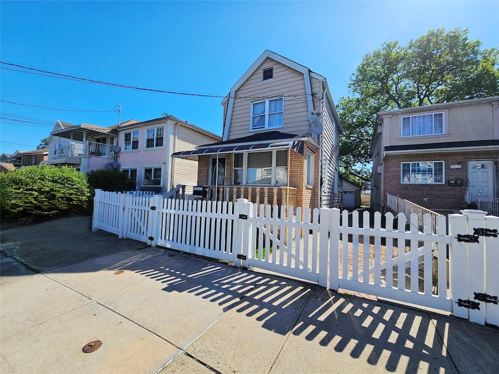 11755 142nd Pl, Jamaica, NY 11436 - view of front of home featuring a gate, a gambrel roof, brick siding, covered porch, and a fenced front yard