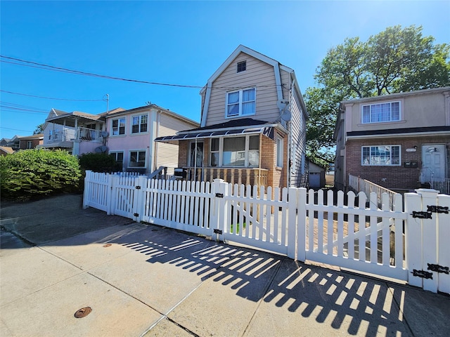 11755 142nd Pl, Jamaica, NY 11436 - view of front of home featuring a gate, a gambrel roof, brick siding, covered porch, and a fenced front yard
