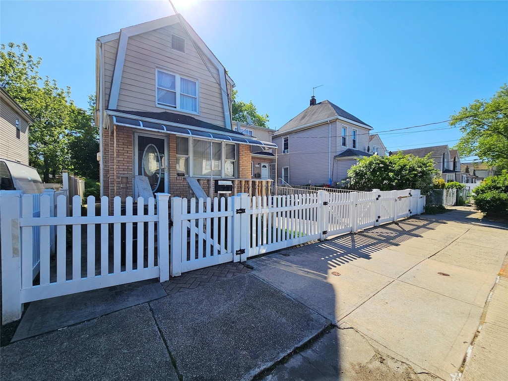 11755 142nd Pl, Jamaica, NY 11436 - dutch colonial featuring brick siding, a fenced front yard, a gate, and a gambrel roof