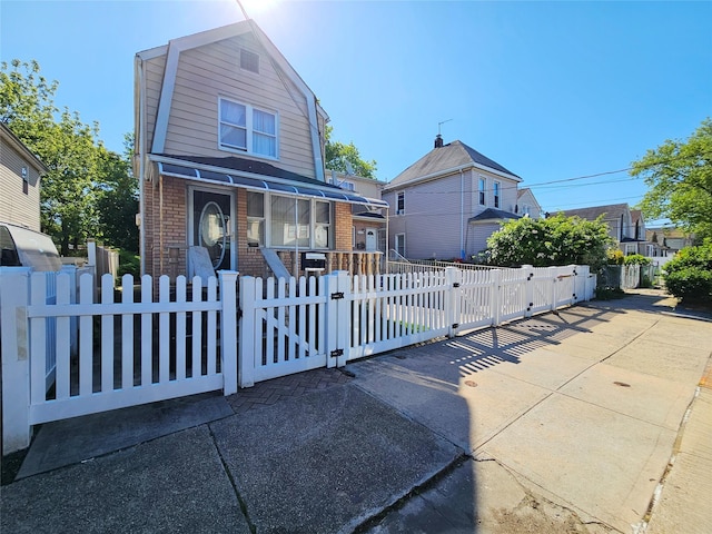 11755 142nd Pl, Jamaica, NY 11436 - dutch colonial featuring brick siding, a fenced front yard, a gate, and a gambrel roof