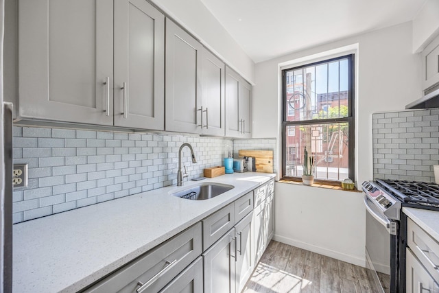 219 Berry St Unit 2, Brooklyn, NY 11249 - kitchen with stainless steel gas range, a sink, light wood-style floors, decorative backsplash, and gray cabinetry