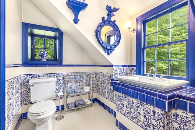 1282 Old Post Rd, Ulster Park, NY 12487 - bathroom featuring toilet, vaulted ceiling, plenty of natural light, a wainscoted wall, and tile patterned flooring