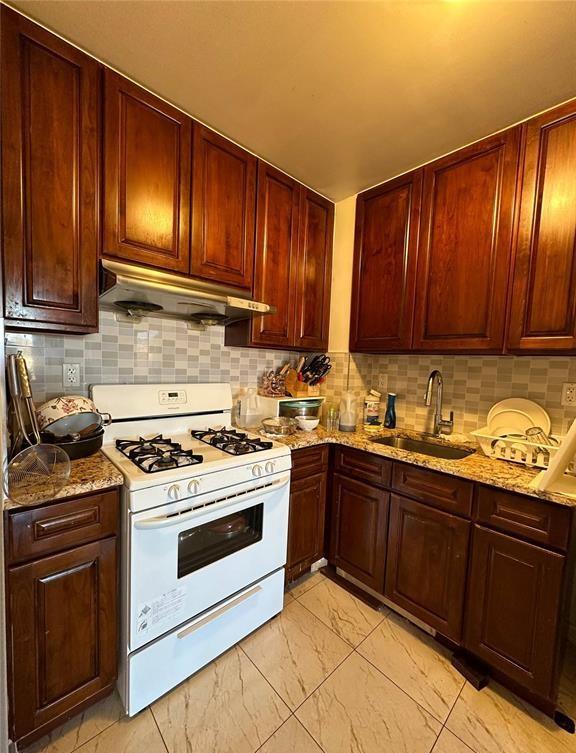 136-21 Latimer Pl Unit 5H, Flushing, NY 11354 - kitchen with white gas stove, under cabinet range hood, a sink, light marble finish flooring, and light stone countertops