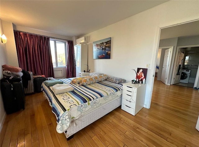 136-21 Latimer Pl Unit 5H, Flushing, NY 11354 - bedroom featuring washer / dryer, an AC wall unit, and hardwood / wood-style floors