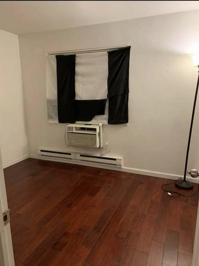 154-11 17th Ave, Whitestone, NY 11357 - spare room featuring a baseboard heating unit, dark wood finished floors, baseboards, and a wall mounted air conditioner