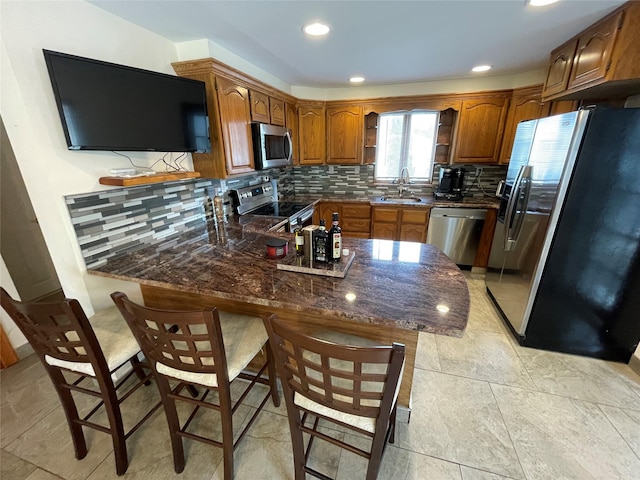 74 Webster Ave, West Islip, NY 11795 - kitchen featuring appliances with stainless steel finishes, a peninsula, a sink, brown cabinets, and recessed lighting