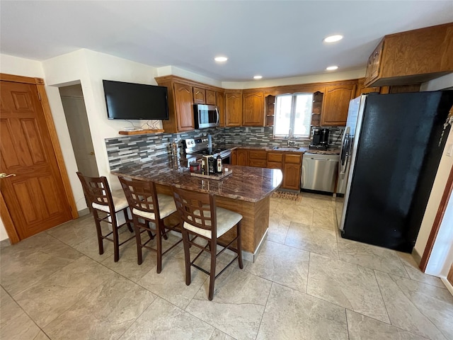 74 Webster Ave, West Islip, NY 11795 - kitchen featuring appliances with stainless steel finishes, brown cabinets, tasteful backsplash, a peninsula, and recessed lighting