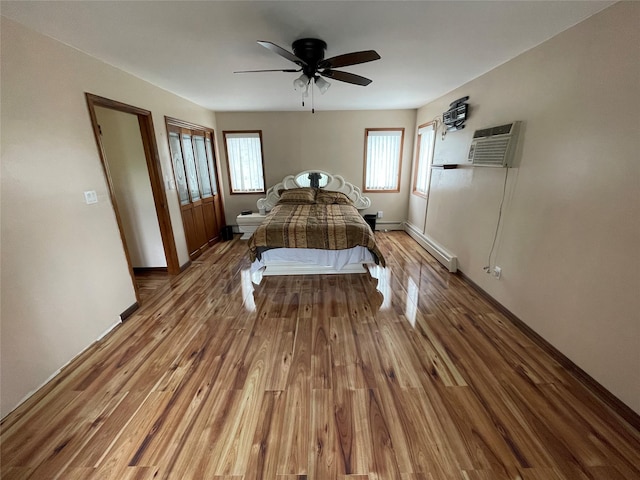 74 Webster Ave, West Islip, NY 11795 - bedroom featuring a baseboard radiator, wood finished floors, a wall unit AC, baseboards, and a ceiling fan
