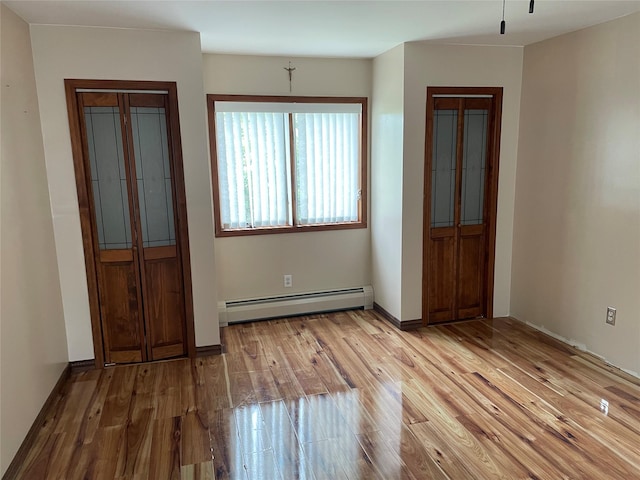 74 Webster Ave, West Islip, NY 11795 - empty room featuring a baseboard heating unit, wood finished floors, and baseboards